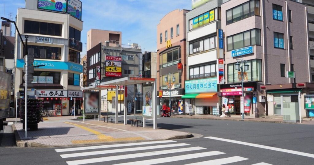 下町のバス停と飲食店が立ち並ぶ駅前風景